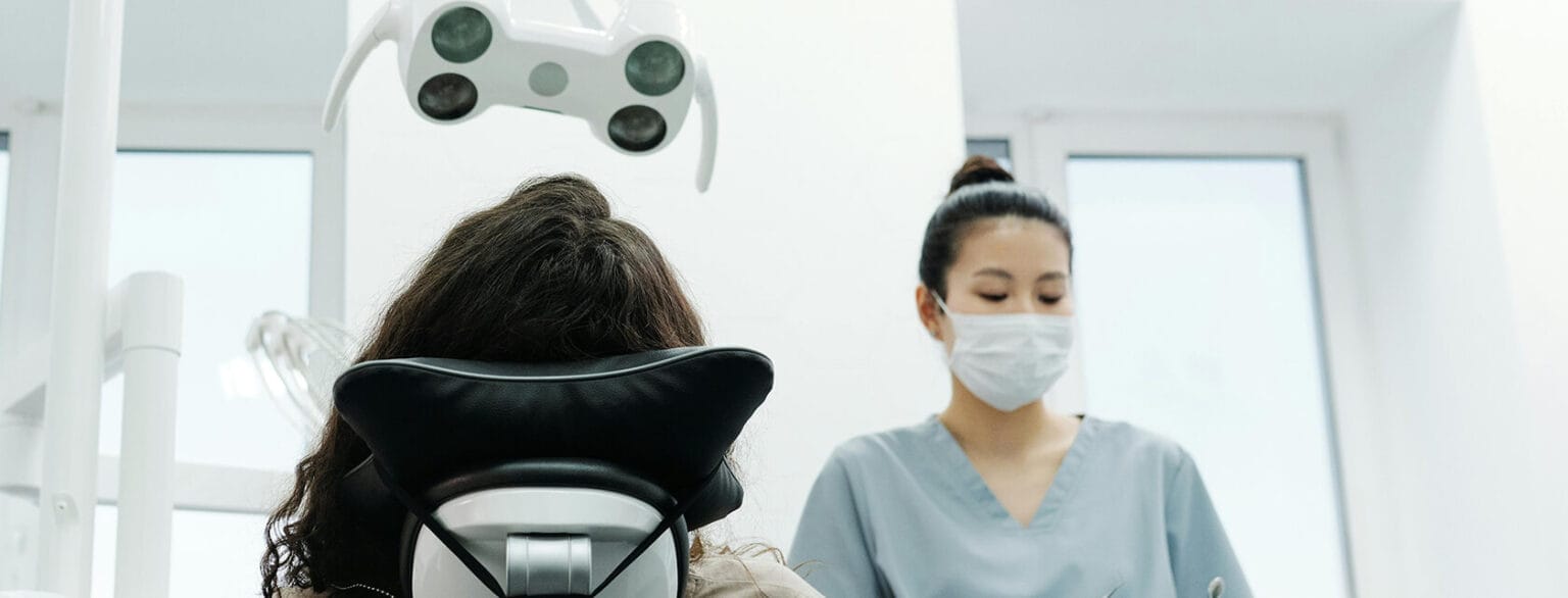 A woman with a mask is present in a dental office