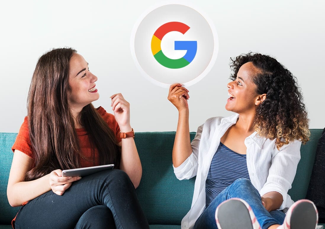 Two people sitting on a sofa, one holding a tablet and the other holding a Google logo.