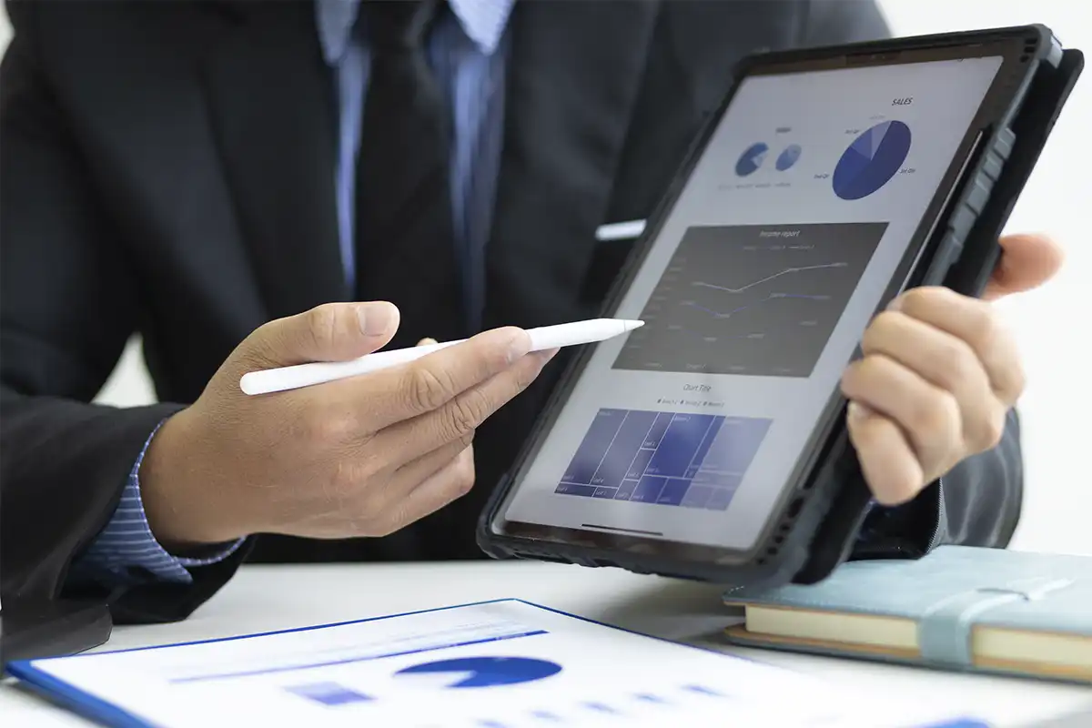 a business professional in a suit presenting data on a tablet screen using a stylus, with charts and graphs visible, indicating the results of using ai lead generation
