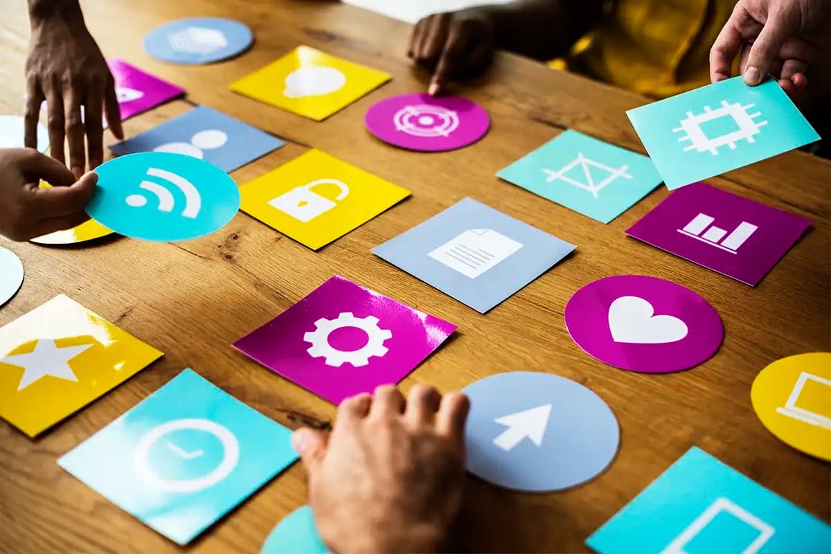 a group of people arranging colorful icon cards on a wooden table, representing social media marketing agency las vegas