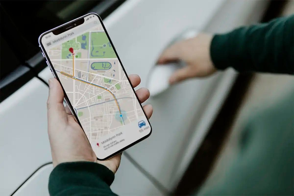 a person holding a smartphone displaying a navigation map while opening a car door, indicating the work of a google maps marketing agency and local seo services