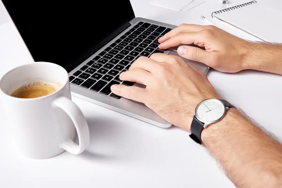 a person typing on a laptop keyboard with a cup of coffee nearby, representing web design services las vegas