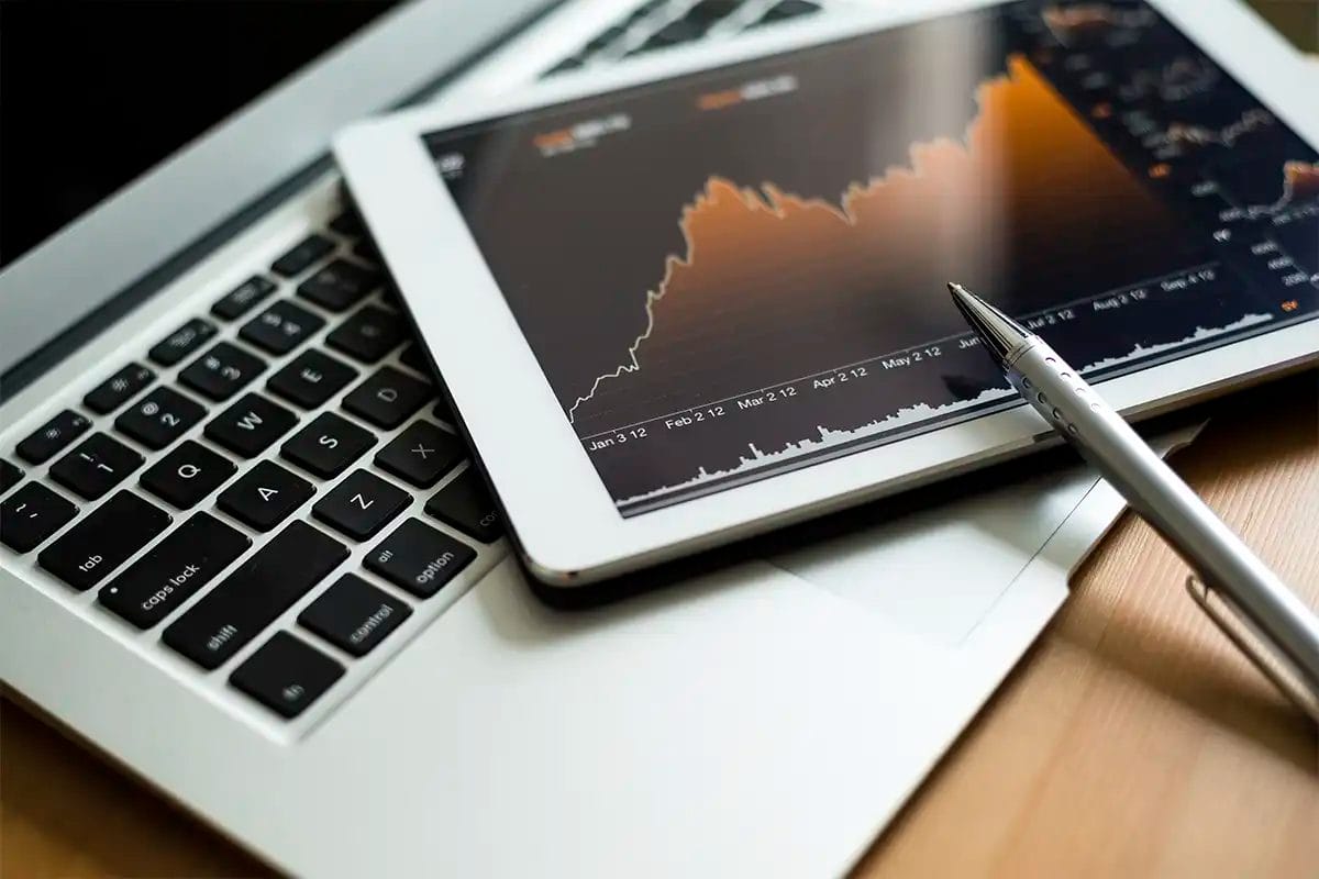 a tablet displaying a rising stock chart placed on a laptop keyboard, with a pen pointing at the chart, symbolizing the results of working with a web design services las vegas
