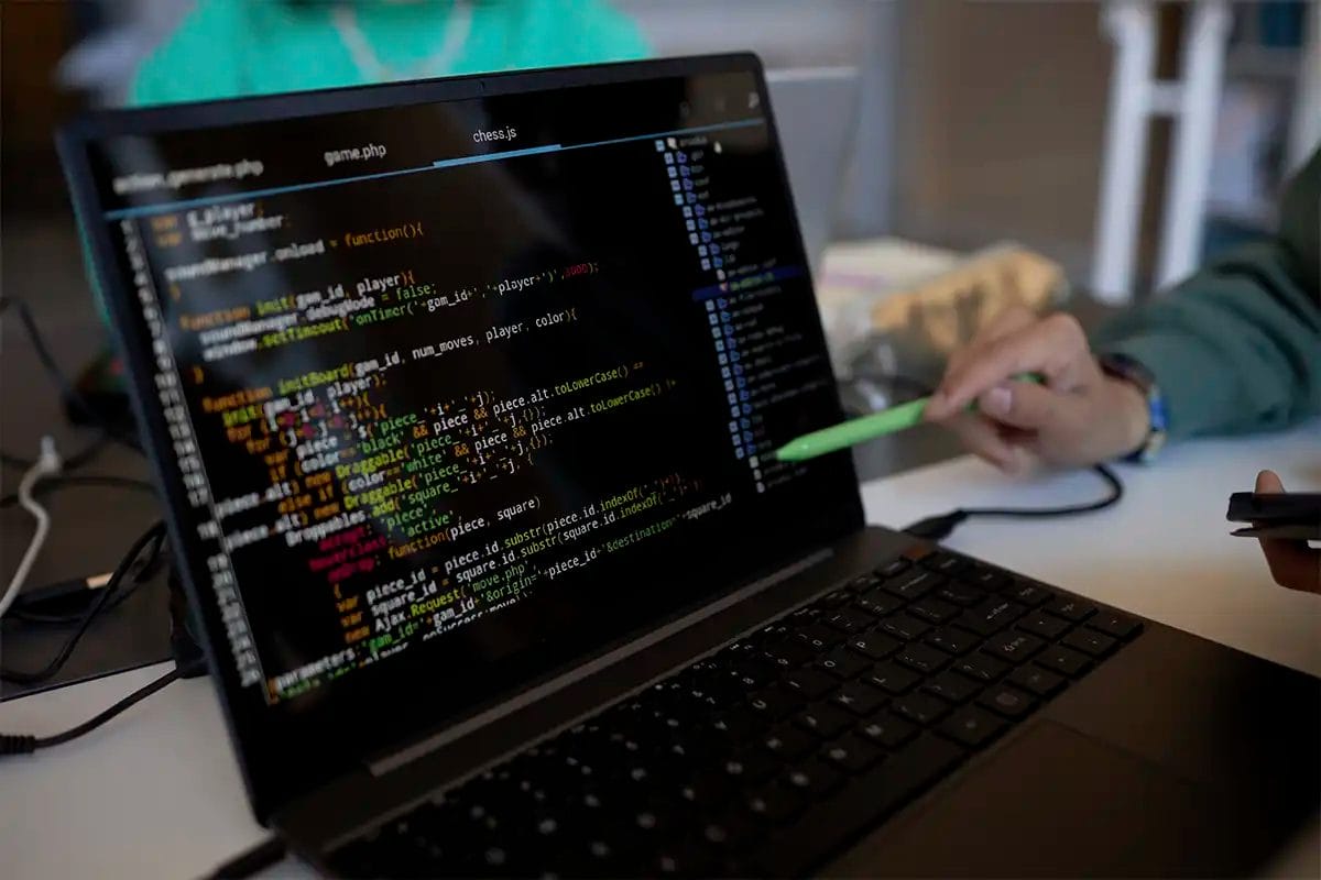 close up of a laptop screen showing a code editor with colorful programming code, while a person points at the screen with a green pen, symbolizing technical seo services