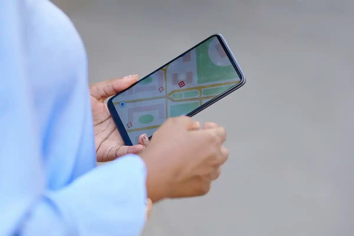 a person holding a smartphone while navigating a digital map searching for a local business, representing google business profile management services